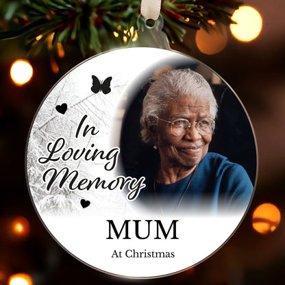 Memorial ornament with an elderly woman's photo and 'In Loving Memory Mum At Christmas' text, hanging against a blurred festive background.
