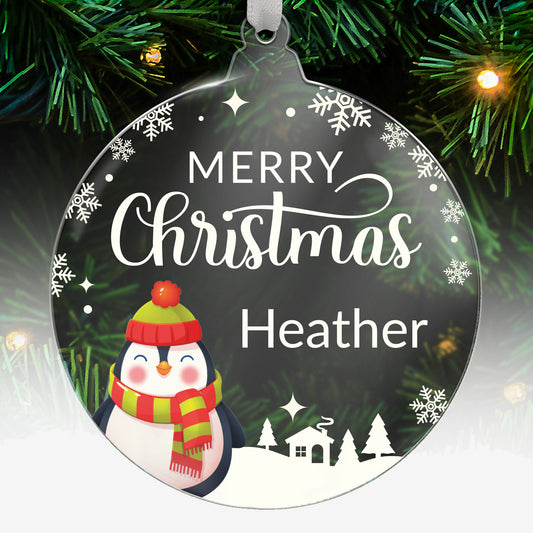 Round acrylic Christmas tree ornament featuring a festive penguin wearing a hat and scarf, with the message 'Merry Christmas' in white and space for custom text below, hanging on a tree with green needles and lights.