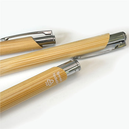 Close-up of several bamboo ballpoint pens, highlighting the natural wood-grain finish, metal clips and recycled material marking.