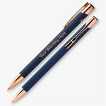 Two navy personalised pens with rose gold detailing, showing the engraved wording and metal pocket clip.