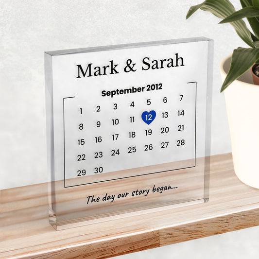A clear plastic block on a shelf, showing names at the top, a calendar with the date 12th September 2012 highlighted and example text "The day our story began..."