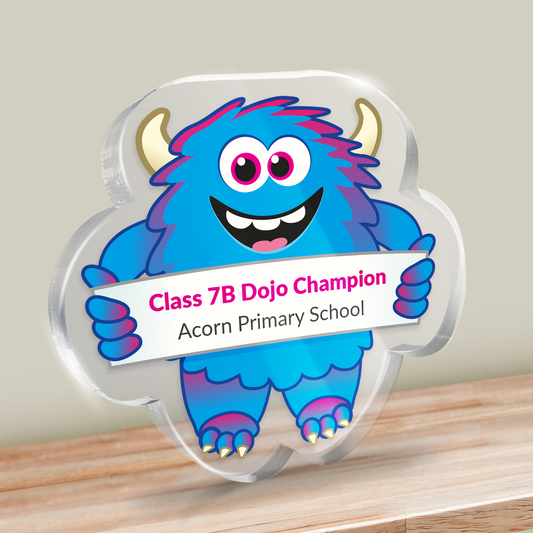 Acrylic blue monster design award with example text: Class 7B Dojo Champion from Acorn Primary School. Shown on a wooden surface.