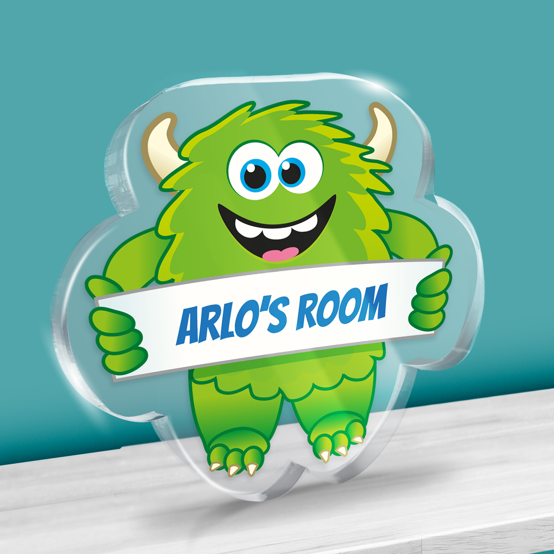 Acrylic green monster block with example text 'ARLO'S ROOM' Shown on a shelf against teal background.