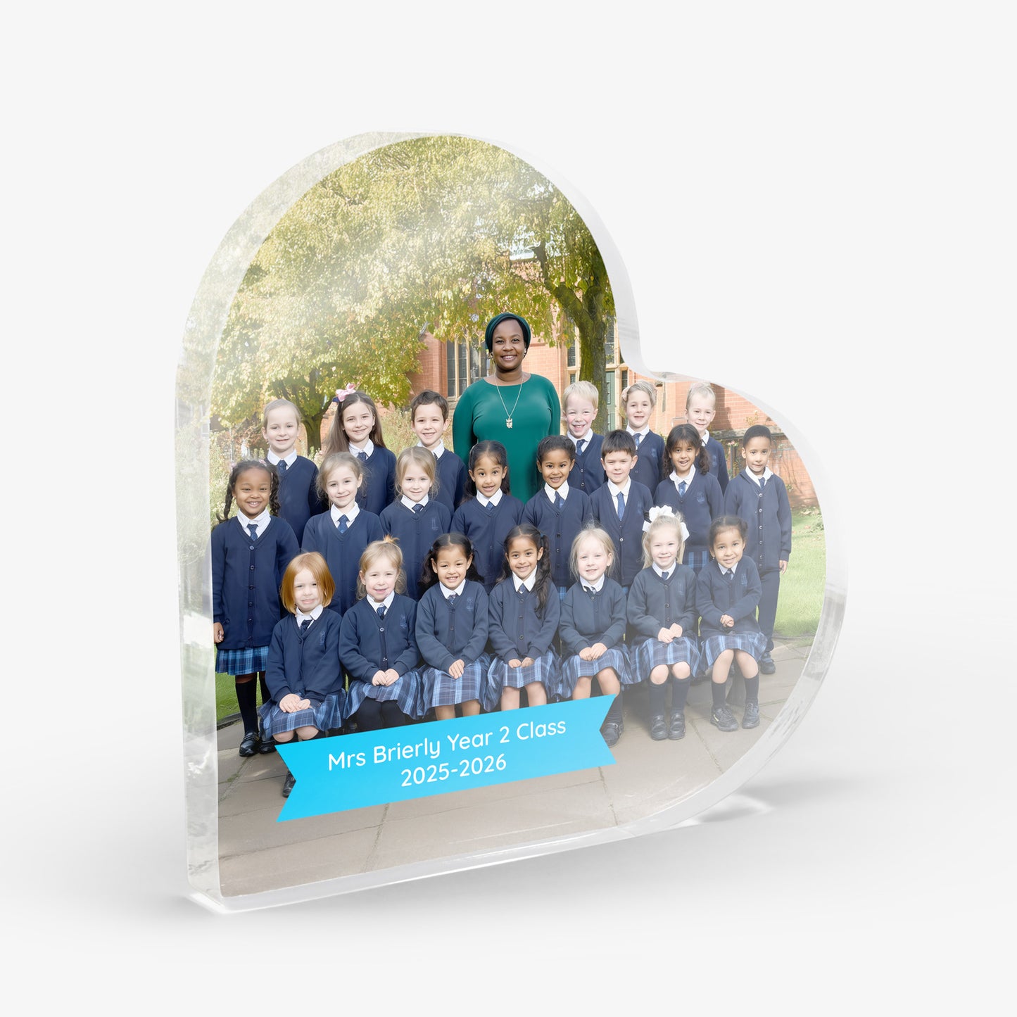 Acrylic heart-shaped photo plaque with a school class photo and teacher. Small blue banner with the text 'Mrs Brierly Year 2 Class 2025-2026'. Shown on a white background.