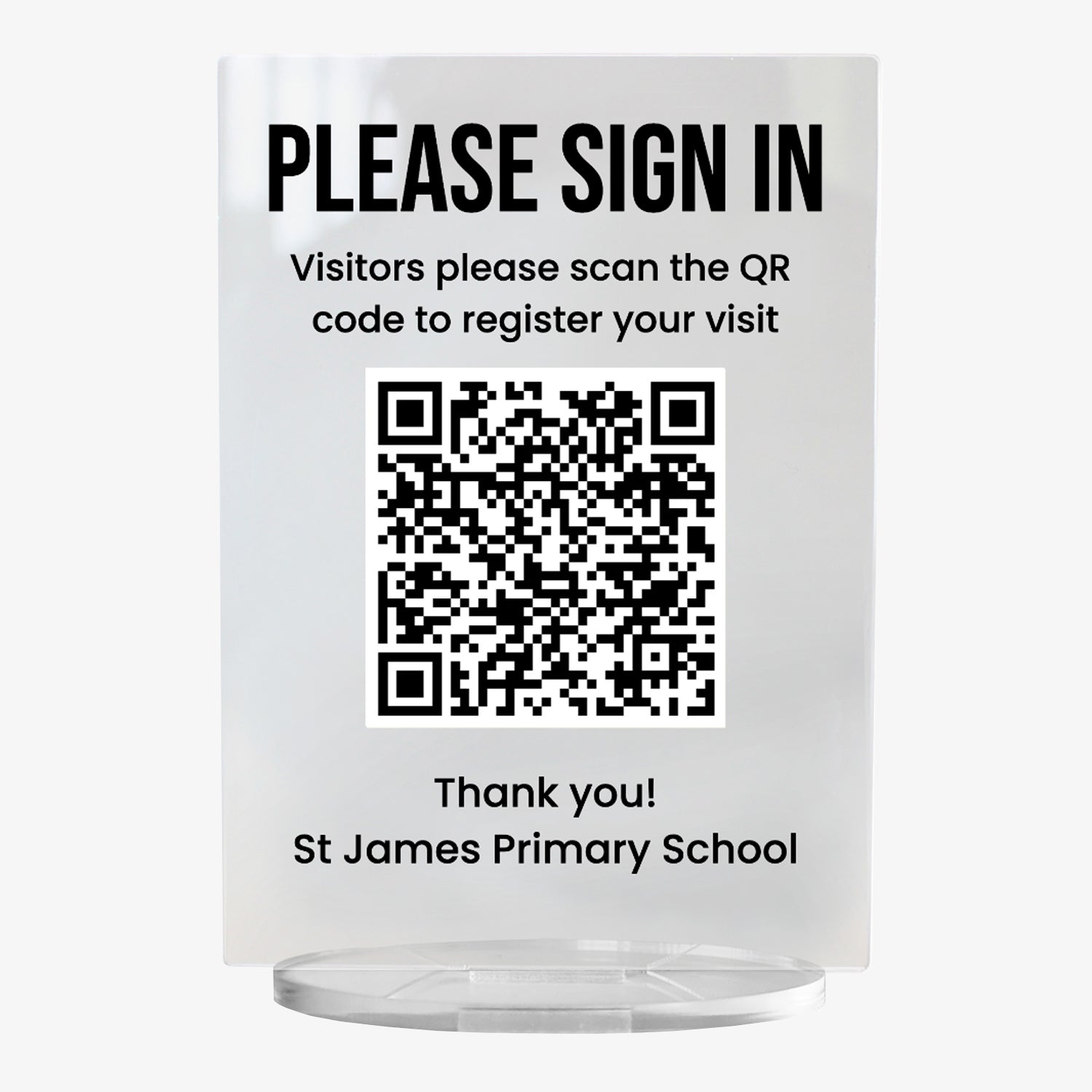 A clear acrylic sign with bold black text at the top reading 'PLEASE SIGN IN'. Below, it says 'Visitors please scan the QR code '. A large black and white QR code to register your visit' is centrally displayed, and the text 'Thank you! St James Primary School' appears at the bottom. The sign stands upright on a circular clear base.