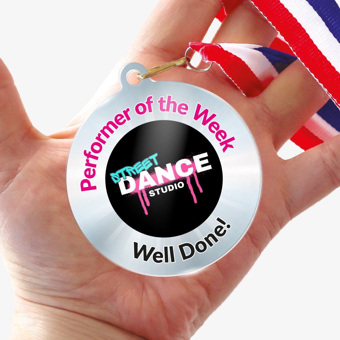 Acrylic personalised medal with stripy ribbon showing silver design with 'Street Dance Studio image' and 'Performer of the Week', 'Well done!' wording. Held in a hand.