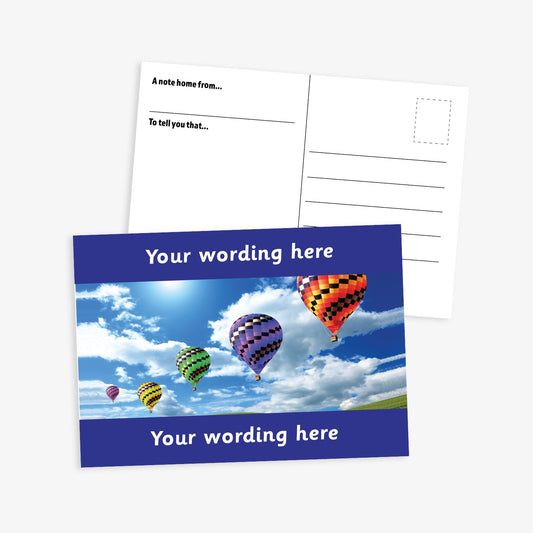 Personalised Hot Air Balloon Postcard from Primary Teaching Services, featuring a vibrant blue border framing a sky scene with multiple colourful hot air balloons floating among clouds. The front side includes the placeholder text 'Your wording here!' in bold white letters, allowing for customisation. The reverse side displays a standard postcard layout with space for a message and address. The postcard measures A6 size and is designed for rewarding pupil achievements.