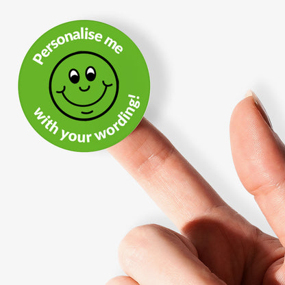 Green sticker, on a finger, with a smiling emoji as the central image.  Space for personalisation above and below the image.