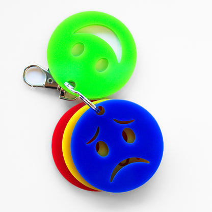 Keyring with four faces showing different emotions. Green smiley face and blue sad face to front.