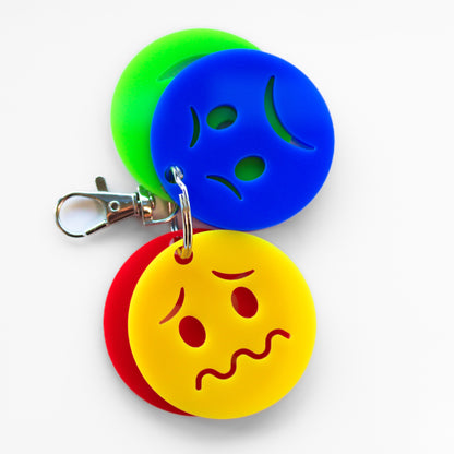Keyring with four faces showing different emotions. Blue sad face and yellow anxious face showing at front.