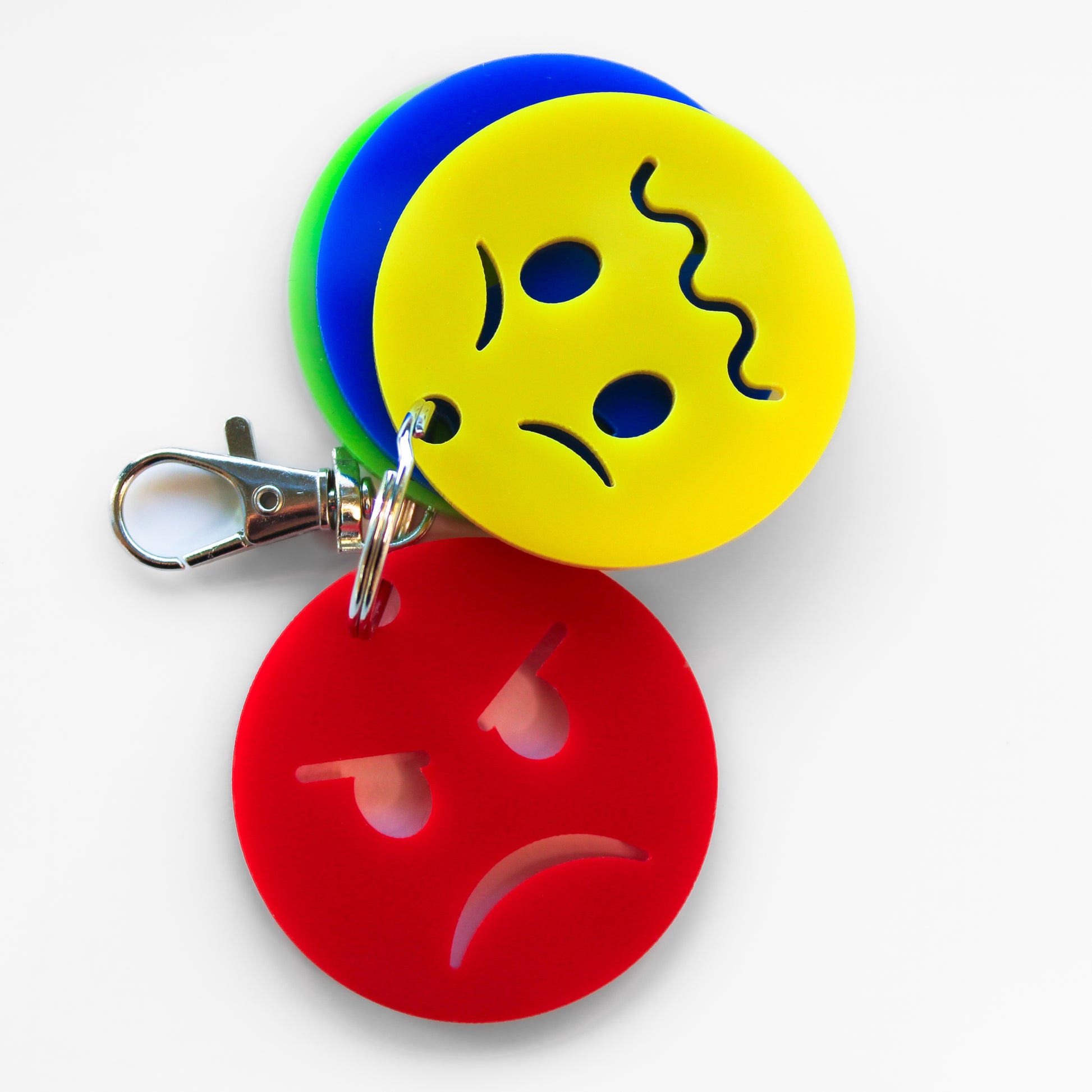 Keyring with four faces showing different emotions. Yellow anxious face and red angry face at the front.