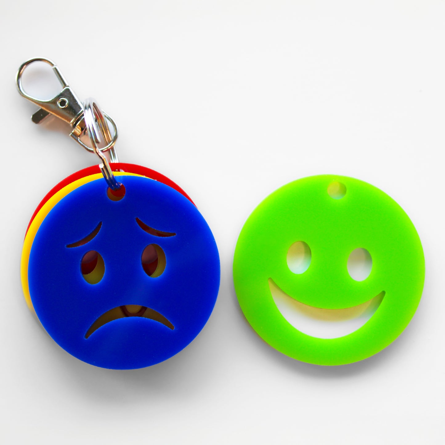 Keyring with four faces showing different emotions. Green happy face separated from rest of keyring. Blue sad face at the front of the keyring.