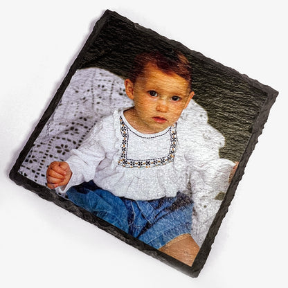 Slate coaster with a photo of a child wearing a white top and blue pants.