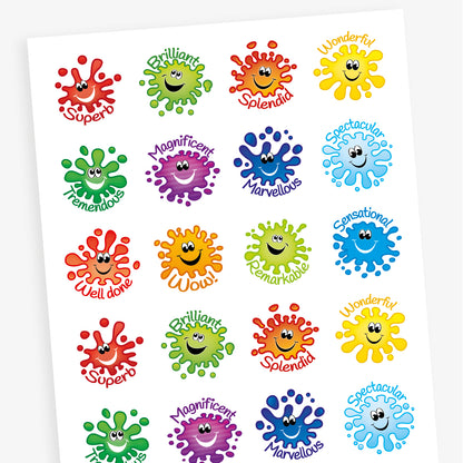 A sheet of circular reward stickers featuring colourful paint splat characters with smiling faces. Each sticker has a positive word in playful font, including 'Superb', 'Brilliant', 'Tremendous', and 'Magnificent', in matching colours to the splats.