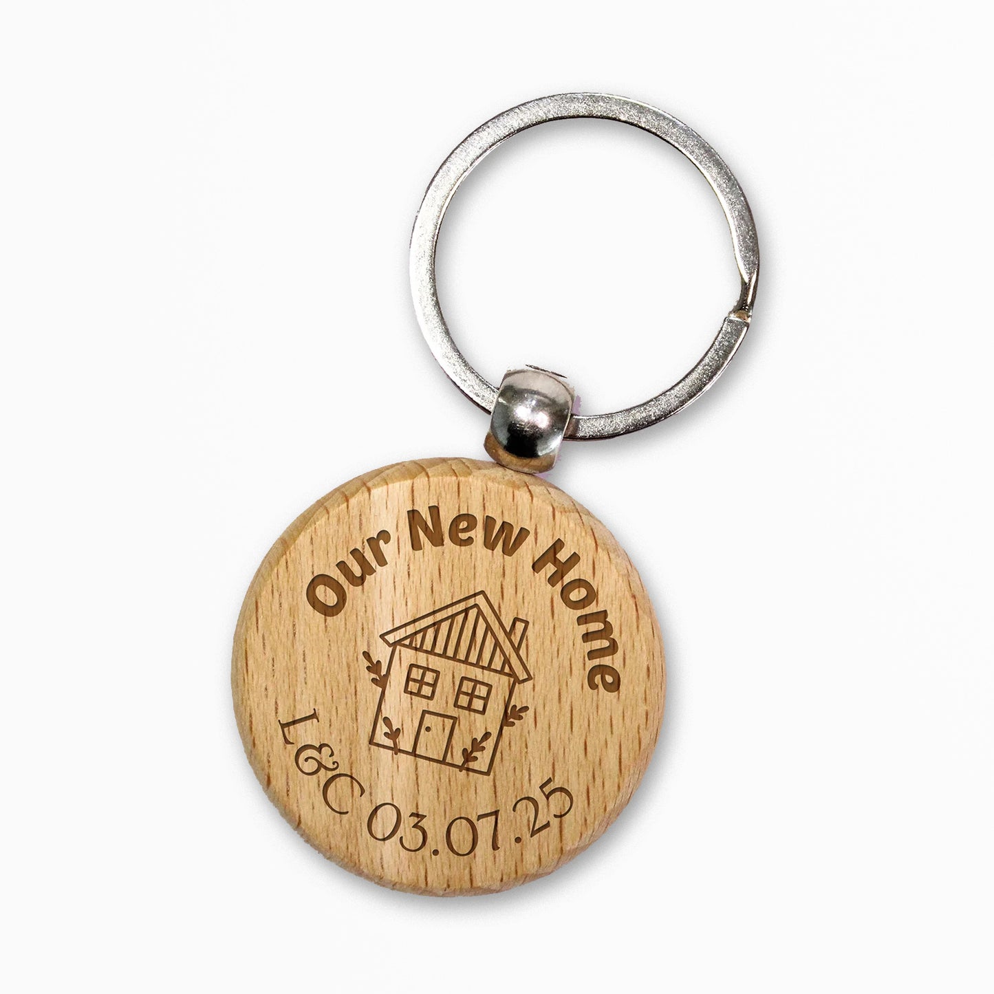 Circular wooden keyring with a metal ring, engraved with text for customisation saying 'Our New Home' a central image of a house etched and underneath 'L&C 03.07.25' 