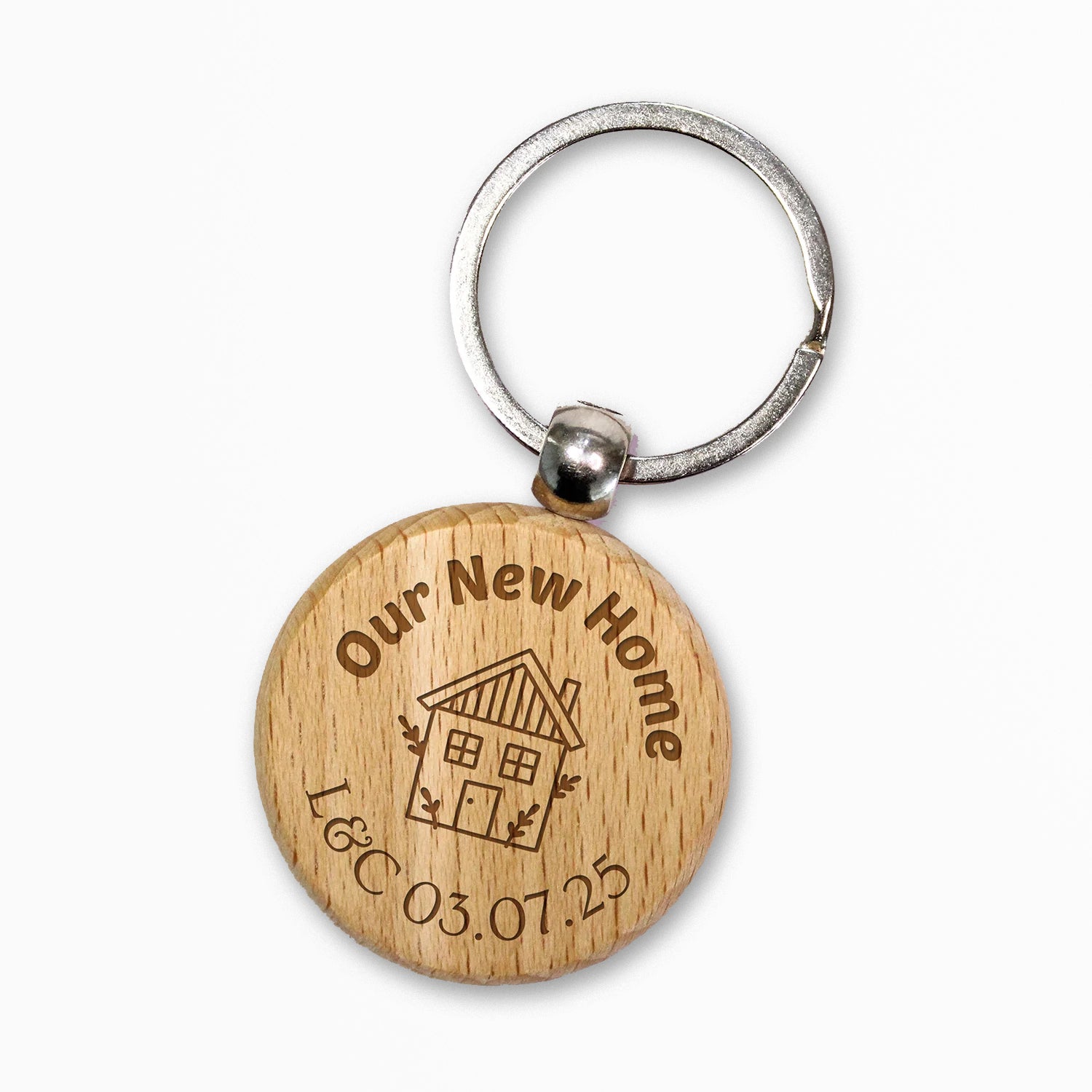 Circular wooden keyring with a metal ring, engraved with text for customisation saying 'Our New Home' a central image of a house etched and underneath 'L&C 03.07.25' 