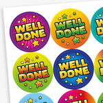 Close-up view of colourful circular Well Done reward stickers with bright comic-style star designs for pupils