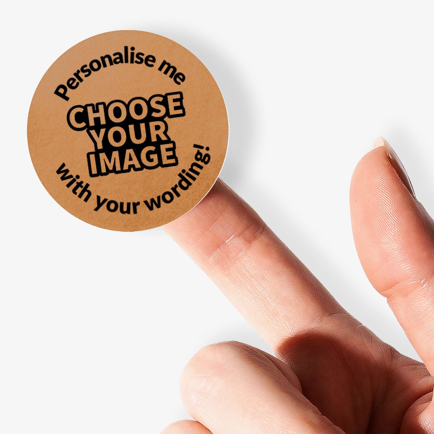 Round brown sticker with text 'Personalise me, choose your image with your wording!' held by a finger on a white background.