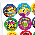 A sheet of 32mm round reading reward stickers featuring vibrant designs with cartoon book characters and phrases such as 'Good Reading', 'Star Reader', 'Excellent Reading', and 'Wonderful Reading'. Each sticker showcases a unique colour scheme and cheerful illustration to encourage young readers