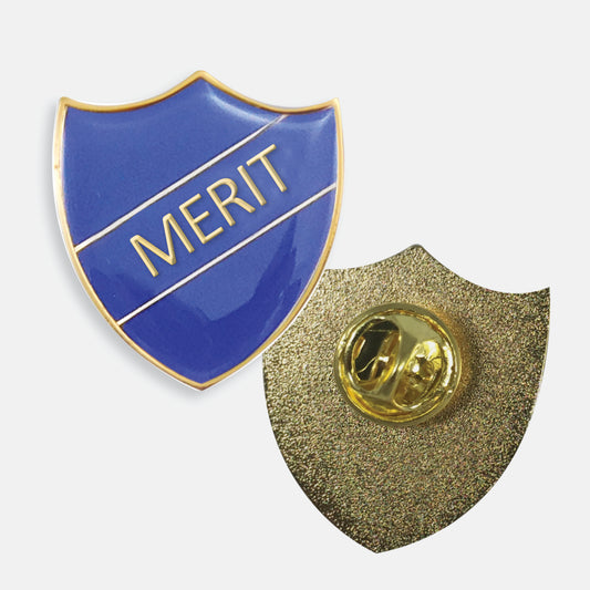 Blue enamel badge in the shape of a shield with gold trim and diagonal gold line either side of the word 'MERIT' in capital letters. The reverse side shows a textured gold back with a pin fastening