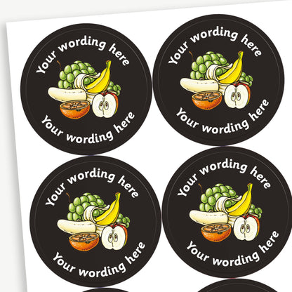 A sheet of circular stickers with a black background. Each sticker features a selection of fruit as a central image including a bunch of grapes, a peeled banana and half an apple and orange. The placeholder 'Your wording here' is written in white font above and below the image.