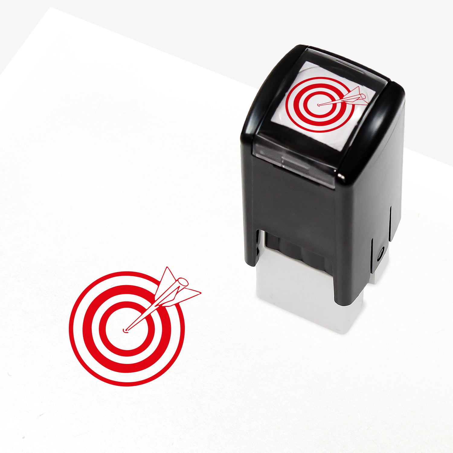 Target Stamper from Primary Teaching Services, featuring a compact black casing with a red bullseye and arrow design. The stamp imprint measures 10mm in diameter and is available in various ink colours, ideal for marking pupil achievements.