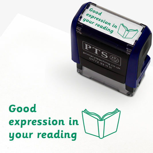 Rectangular self-inking stamper measuring 38mm by 15mm, featuring the phrase 'Good expression in your reading' in green text alongside an open book icon; available in green or purple ink, ideal for providing feedback in pupils' reading records and homework diaries.