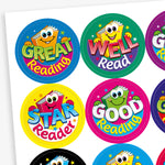 Sheet of colourful round reading reward stickers featuring cartoon book characters with smiling faces. Phrases include 'Great Reading', 'Well Read', 'Star Reader', and 'Good Reading', each in bold, playful fonts on vibrant backgrounds such as blue, green, yellow, and pink.